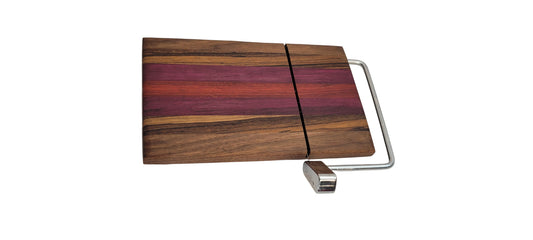 A cheese slicer made of butcher block with a silver handle, featuring a layered design with different wood colors including purple and black, and a branded logo on the back.