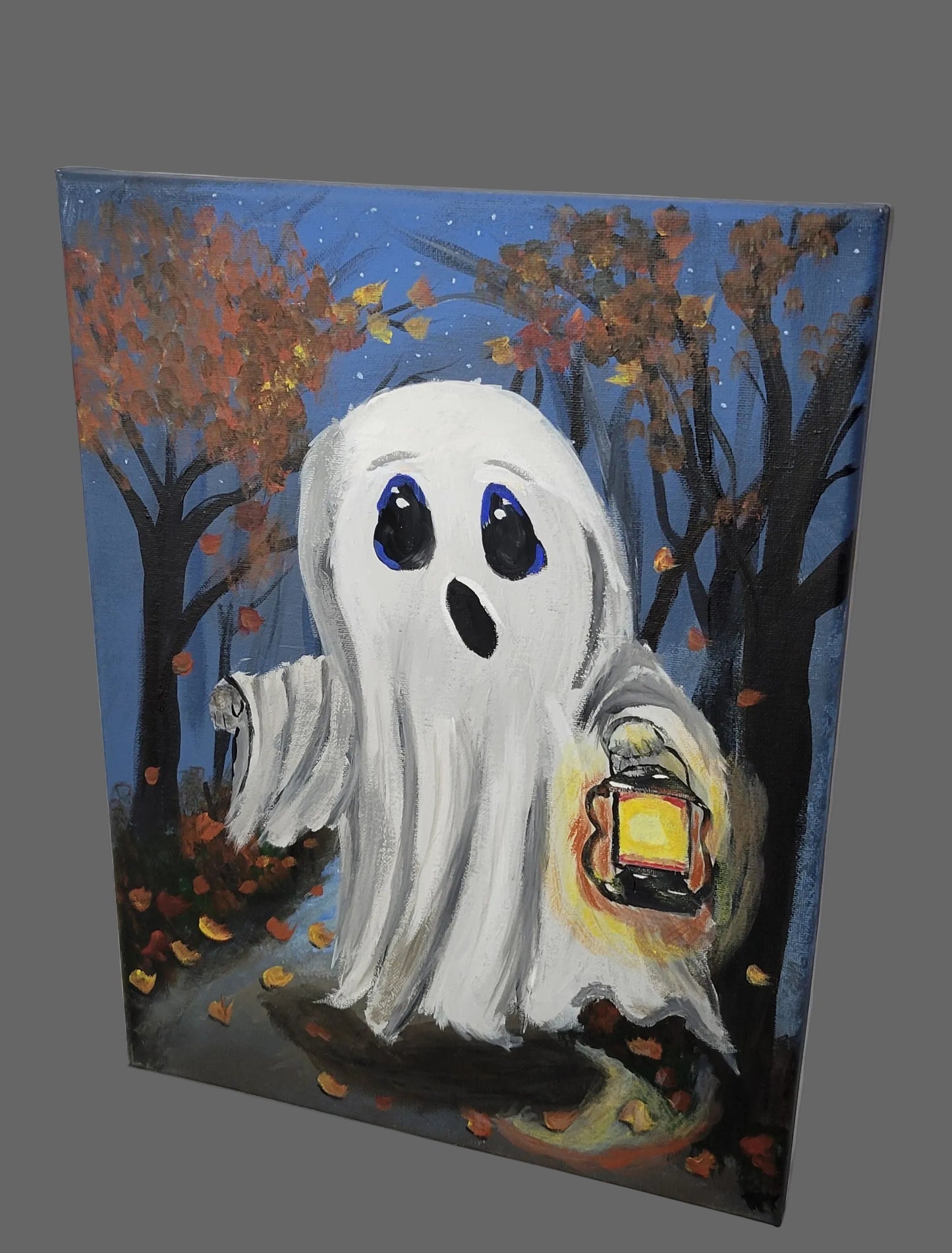 Hand-painted canvas wall art depicting a cute white ghost with blue eyes holding a lantern, in a forest setting with autumn leaves and a twilight sky.