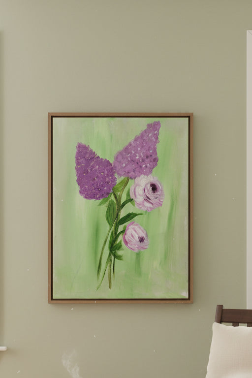 Rocking chair with a pillow and blanket in a room with a painting of flowers on the wall.