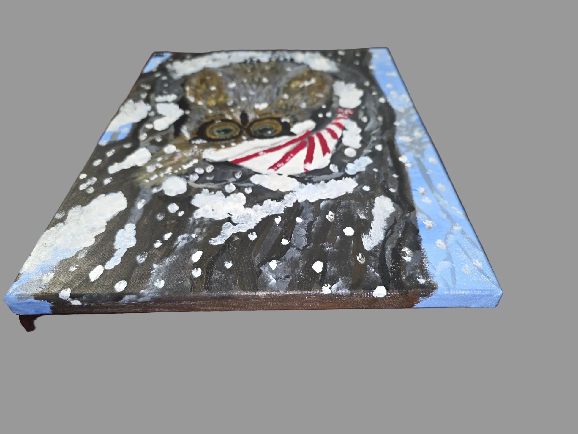 Painting of a cat with a blue border on a wooden surface